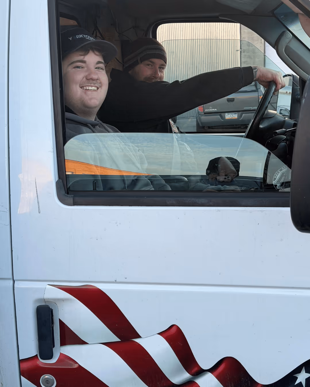 Two smiling Yorktowne team members in the cab of a company van