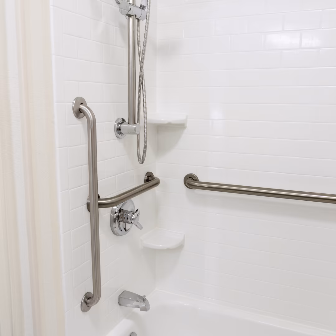 Shower with grab bars, a handheld sprayer, and a built-in seat