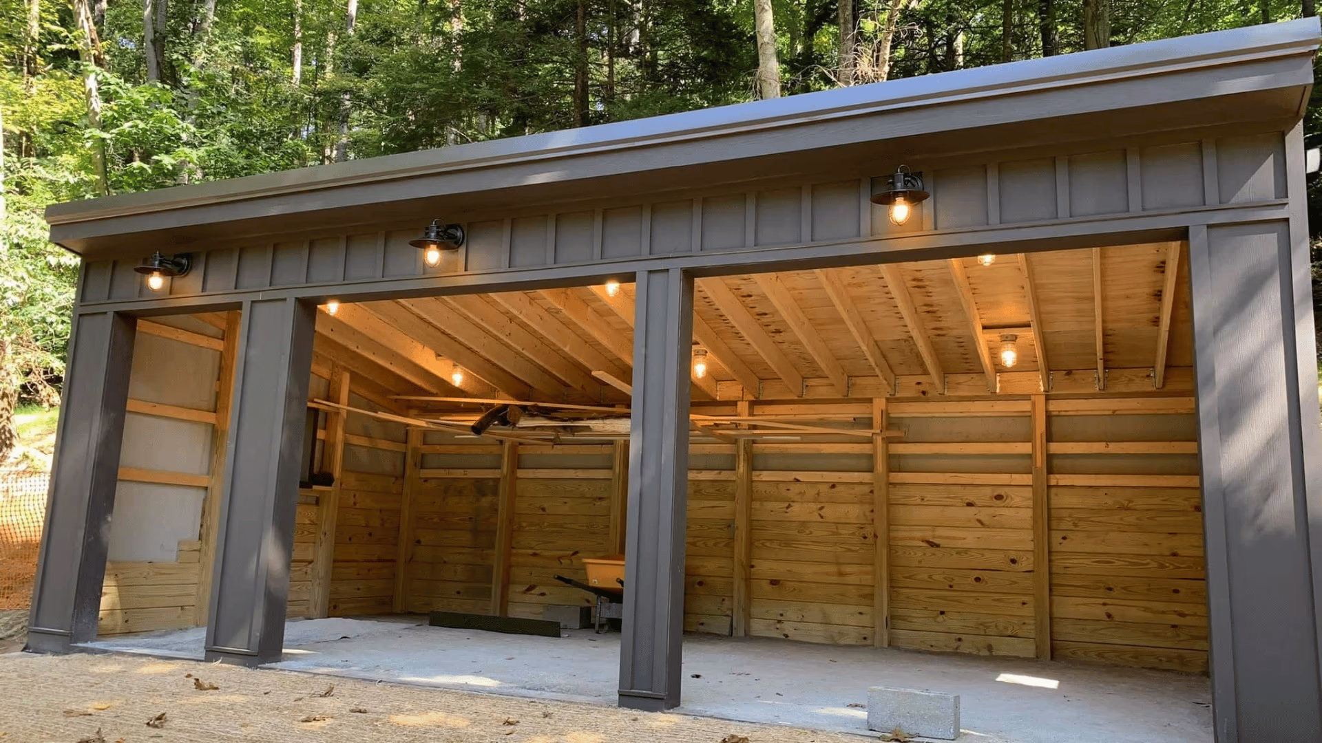 Finished pavilion with exterior lights on at a wooded home