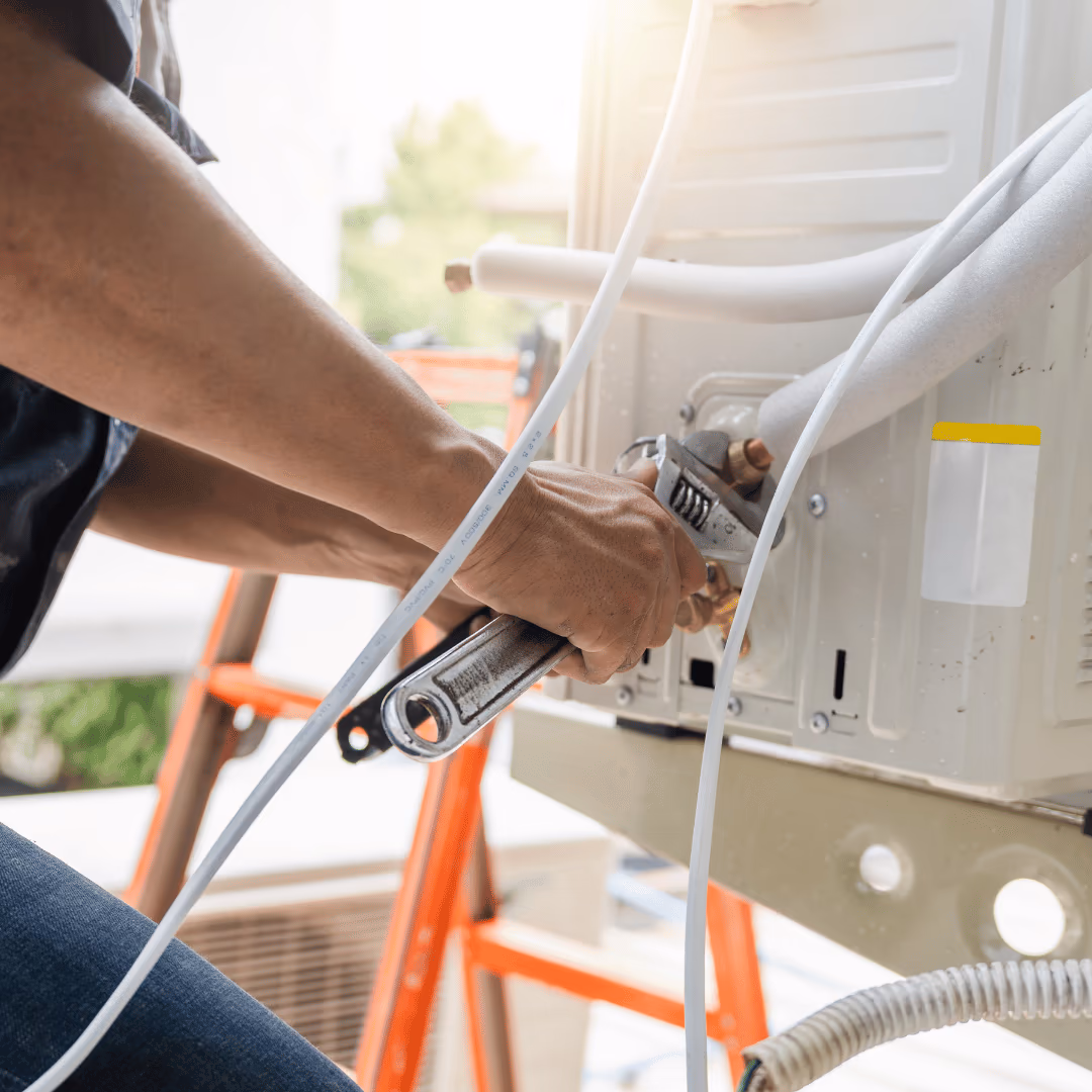 Technician tightening refrigerant lines on an outdoor air conditioner