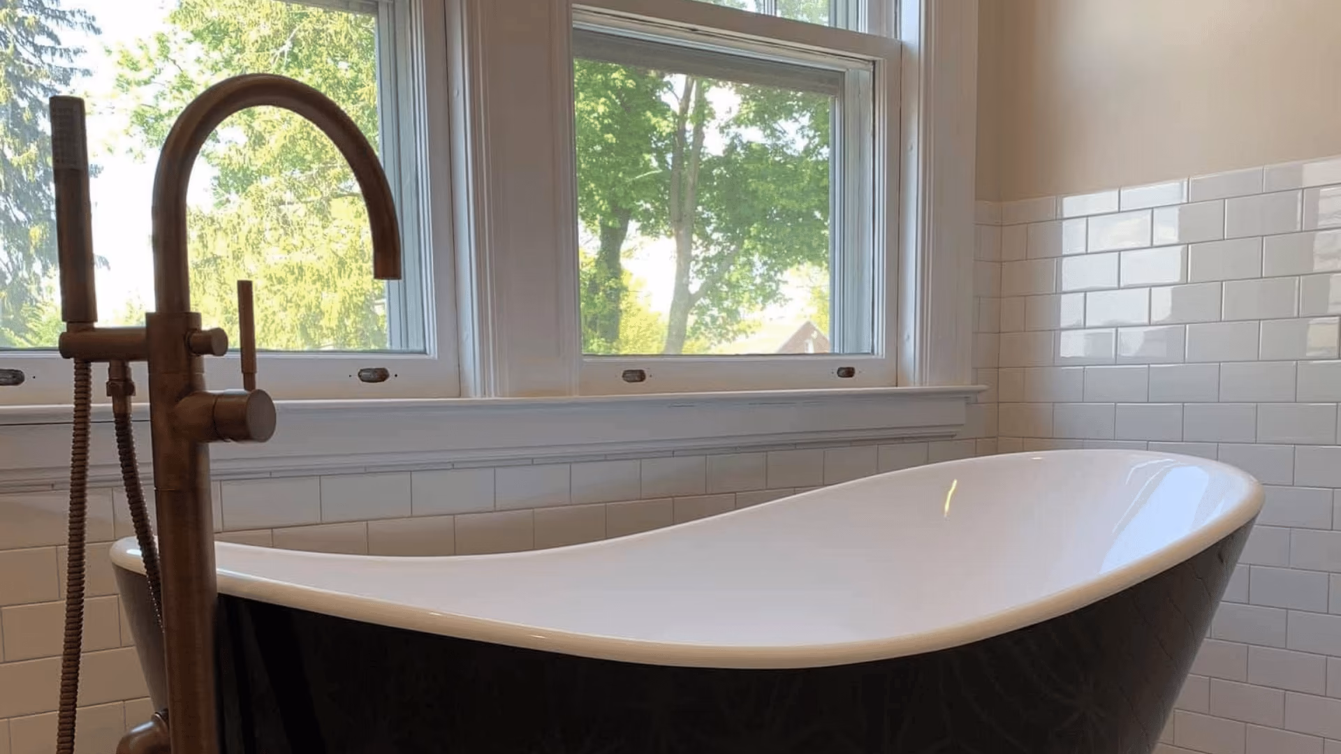 Freestanding bathtub and floor-mount faucet in front of a window