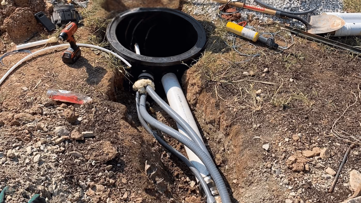 Open drain cleanout with pipes exposed in an excavated yard