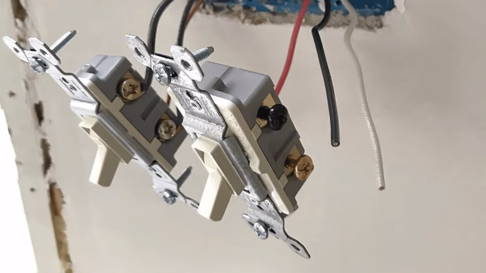 Light switches pulled from a wall box during an electrical repair