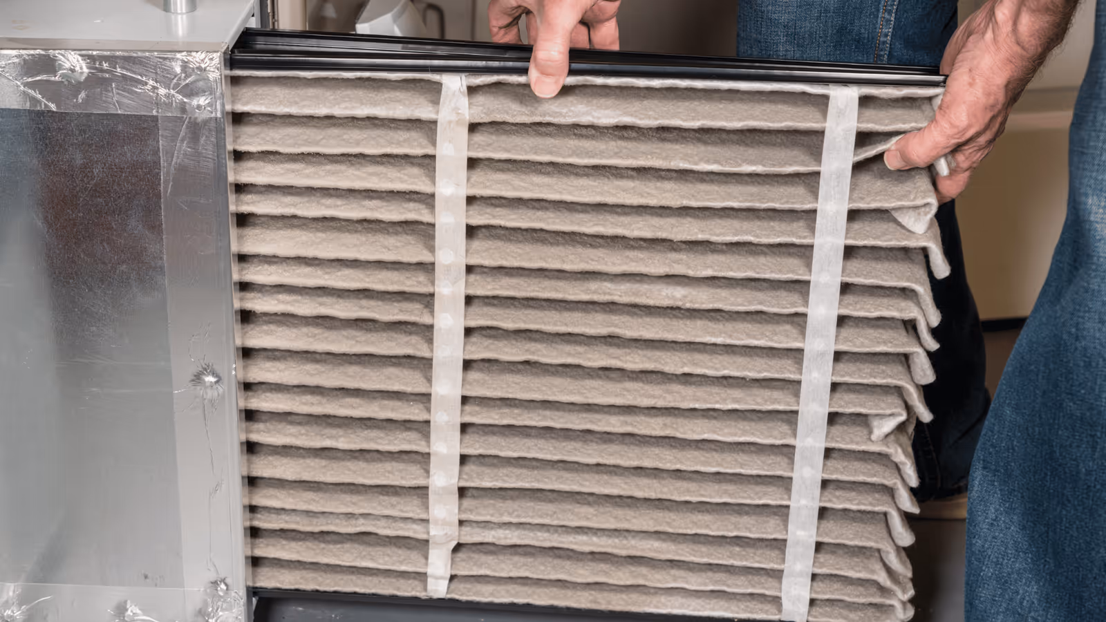 Technician replacing a pleated HVAC air filter